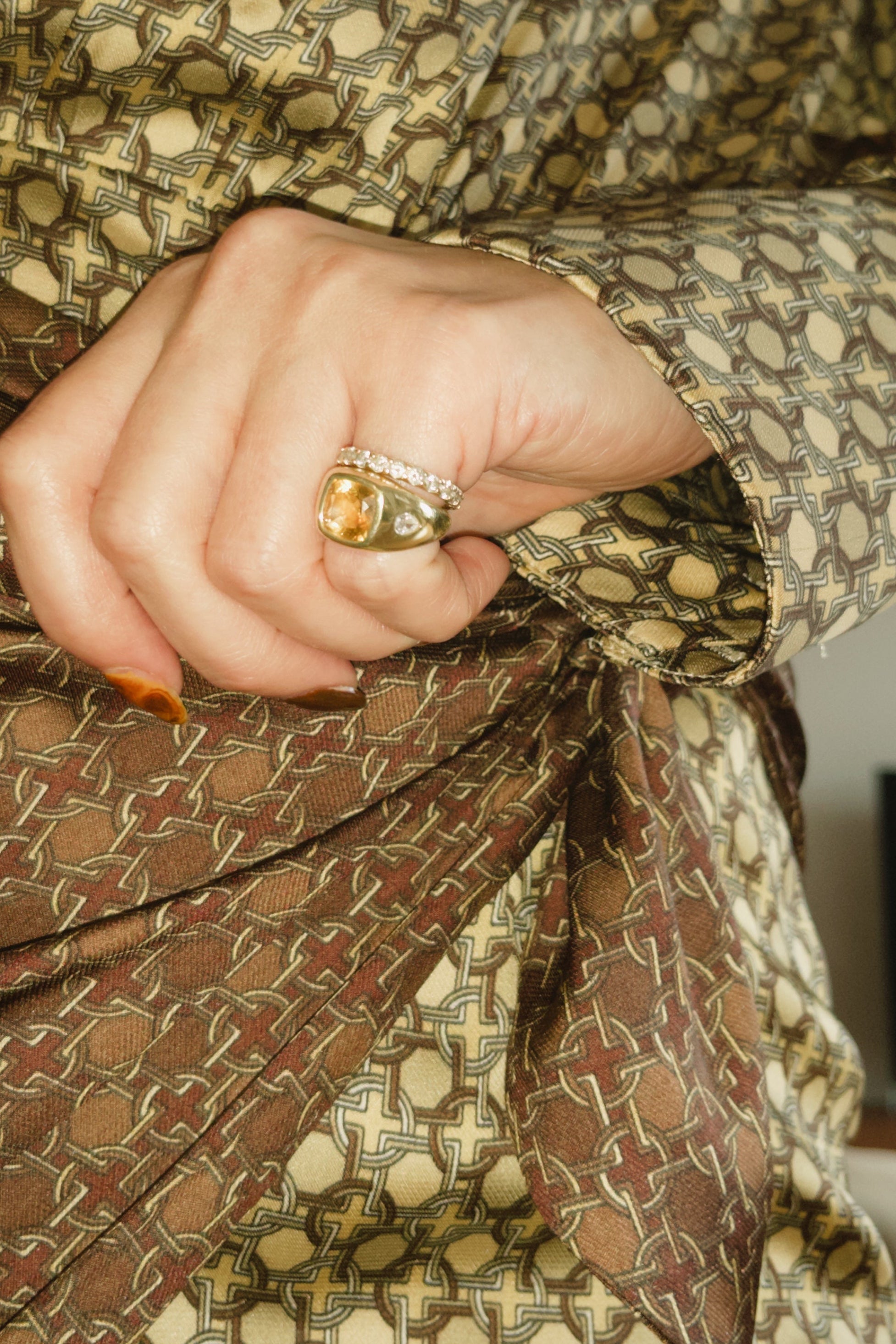 Close-up of a hand wearing a ring with a patterned garment.