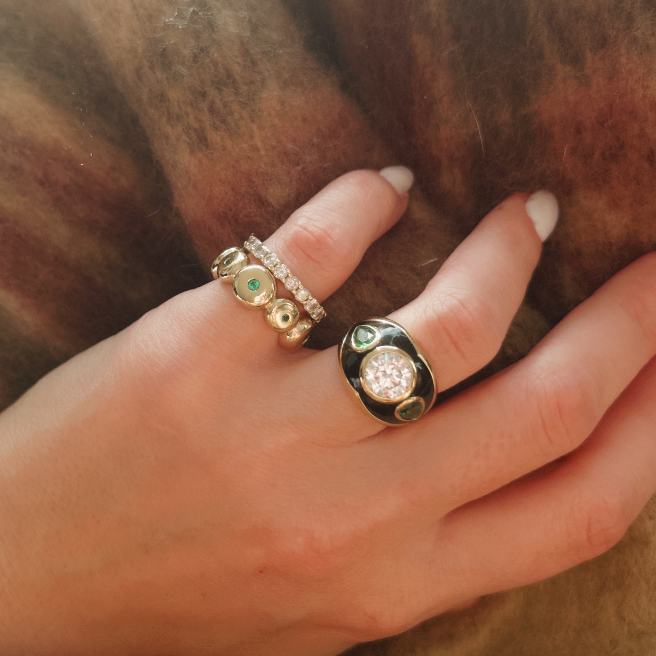 Hand wearing two rings on a textured fabric background